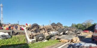 Caminhão carregado de madeira capota na BR-230 e motorista fica preso às ferragens